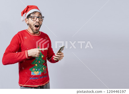 Guy pointing at christmas promotion on phone. Online Christmas special offers concept, amazed people pointing at a Christmas promotion on phone, Amazed man pointing at christmas offer online 120446197