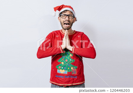Man with christmas hat with hands together in pleading gesture. Christmas guy with hands together begging for a Christmas wish, Person in christmas hat with desperate pleading gesture 120446203