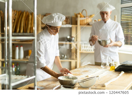 Elderly man and woman kneading and whipping dough 120447605