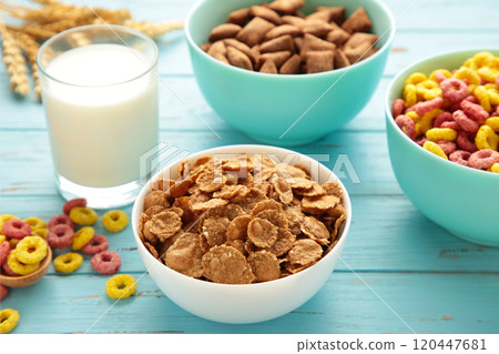 Variety of cereals in blue bowls, quick breakfast and milk on blue wooden background. 120447681