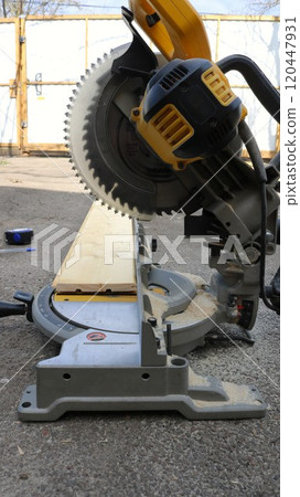 miter saw standing on asphalt in the yard, object without people, processing of wooden material for construction in a private household 120447931
