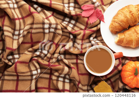 Hot coffee with croissant and autumn leaves on plaid - seasonal relax concept Hot coffee with croissant and autumn leaves on plaid - seasonal relax concept 120448116