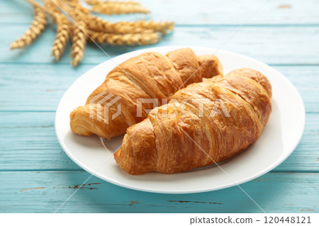 Freshly croissant with wheat on blue background Freshly croissant with wheat on blue background 120448121