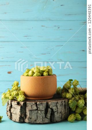 Wooden bowl with hops on blue wooden background, space for text. Vertical photo Wooden bowl with hops on blue wooden background, space for text. Vertical photo 120448391