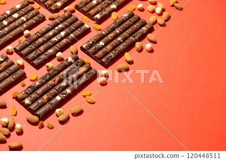 Lots of chocolate bars with nuts and raisins on a red background copy space for text 120448511