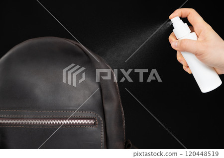 Applying the spray to a leather backpack, accessories care 120448519