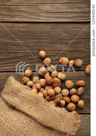 Hazelnuts, filbert in burlap sack on grey wooden backdrop. Hazelnut background, healty food. Vertical photo Hazelnuts, filbert in burlap sack on grey wooden backdrop. Hazelnut background, healty food. Vertical photo 120448540