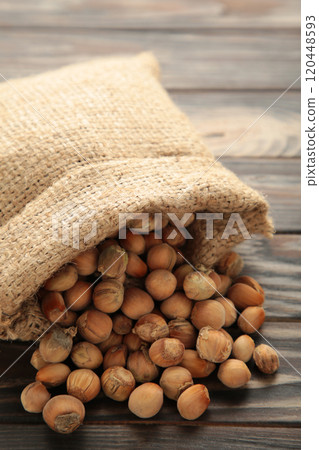 Hazelnuts, filbert in burlap sack on brown wooden backdrop. Hazelnut background, healty food. Vertical photo Hazelnuts, filbert in burlap sack on brown wooden backdrop. Hazelnut background, healty food. Vertical photo 120448593