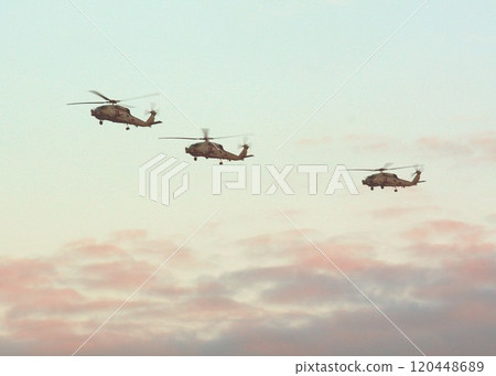 U.S. Navy carrier-based MH-60R Seahawk maritime patrol utility helicopters flying in formation in the crimson evening sky. 120448689