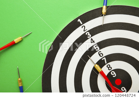 Dart board with blue and red darts on green background. Dart board with blue and red darts on green background. 120448724