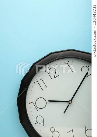 Black wall clock on the blue background. 120448732
