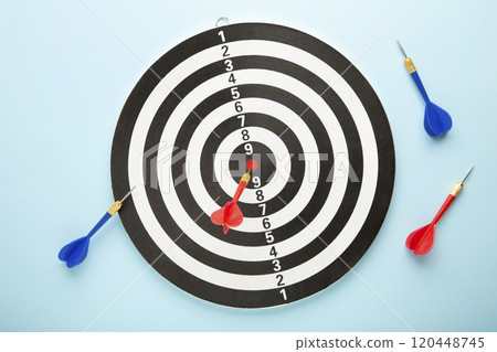 Dart board with red darts on blue background. Dart board with red darts on blue background. 120448745