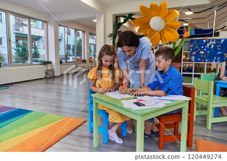 Creative kids during an art class in a daycare center or elementary school classroom drawing with female teacher. Creative kids during an art class in a daycare center or elementary school classroom drawing with female teacher. 120449274