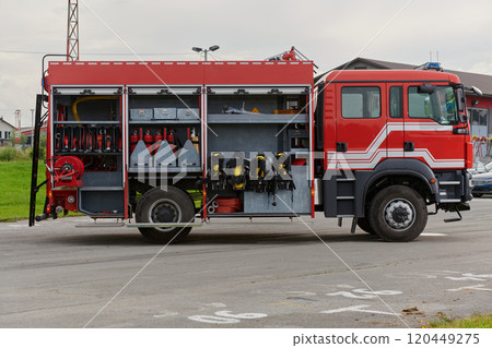 In this captivating scene, a state-of-the-art firetruck, equipped with advanced rescue technology, stands ready with its skilled firefighting team, prepared to intervene and respond rapidly to 120449275