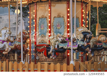 Closeup of vintage carousel featuring ornate horses and glowing decorative lights 120449565