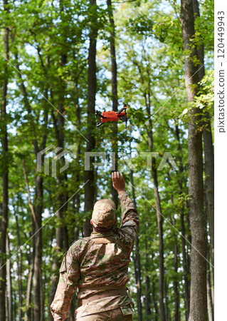 Elite military unit, equipped with state-of-the-art technology including a drone, strategically navigates and surveys dangerous wooded terrain, showcasing their precision, cooperation, and specialized 120449943