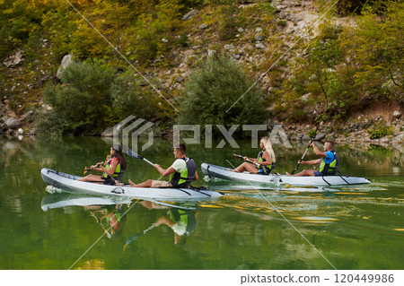 A group of friends enjoying having fun and kayaking while exploring the calm river, surrounding forest and large natural river canyons A group of friends enjoying having fun and kayaking while exploring the calm river, surrounding forest and large natural river canyons 120449986
