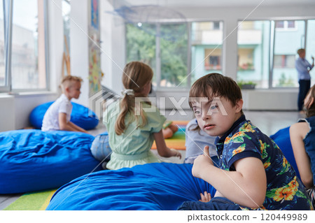 A happy female teacher sitting and playing hand games with a group of little schoolchildren 120449989