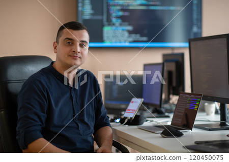 A programmer diligently testing smartphone applications while sitting in their office. 120450075