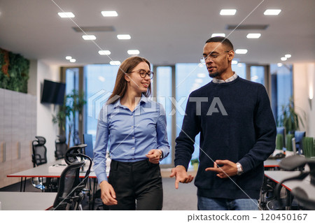 Dynamic Business Collaboration: Blonde Businesswoman and African American Colleague in Modern Office Setting. Dynamic Business Collaboration: Blonde Businesswoman and African American Colleague in Modern Office Setting. 120450167