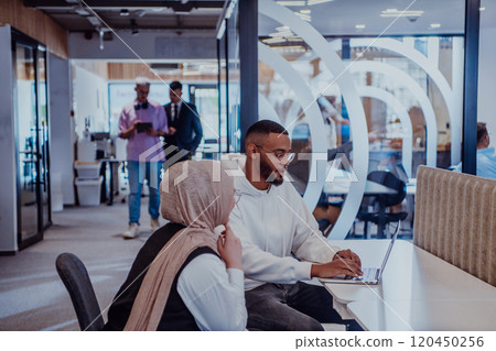 In a modern office setting, an African American businessman and his Muslim colleague, wearing a hijab, engage in collaborative discussions, tackling various business tasks and solving problems In a modern office setting, an African American businessman and his Muslim colleague, wearing a hijab, engage in collaborative discussions, tackling various business tasks and solving problems 120450256
