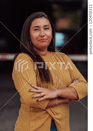A powerful portrait of a businesswoman, standing confidently with her arms crossed, representing the determination of the female gender and embodying strength and success 120450311