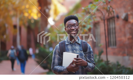 happy african american student with books in his hands against the background of the university campus 120450312