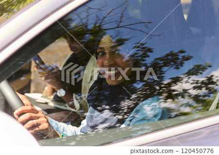 Two Muslim women wearing hijab converse on a smartphone while traveling together in a car through the  120450776