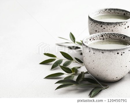 Minimalist composition of ceramic cups with green tea and fresh leaves on a white background 120450791
