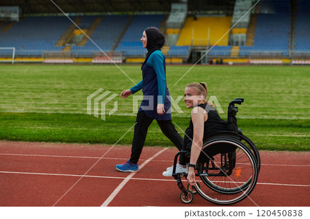 A Muslim woman in a burqa running together with a woman in a wheelchair on the marathon course, preparing for future competitions. 120450838