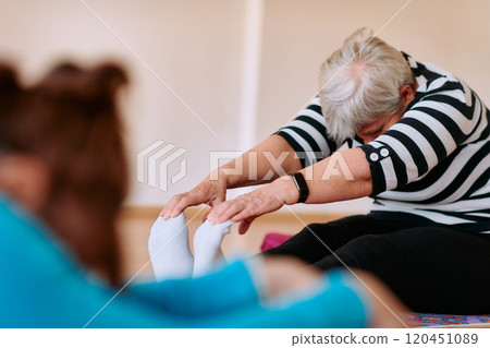 Senior Woman Practicing Back Stretches in a Sunlit Space for Optimal Health and Well Being 120451089