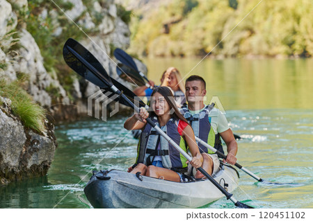 A group of friends enjoying having fun and kayaking while exploring the calm river, surrounding forest and large natural river canyons 120451102