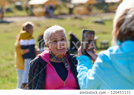 An elderly pair of women captures a timeless moment on their smartphones, blending technology with the serene beauty that surrounds them 120451131