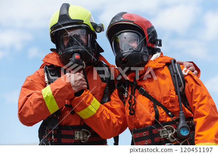 A unified team of firefighters, adorned in their uniforms, engages in a heartfelt celebration marked by triumphant salutes and cheers, embodying the joy and gratitude following the successful 120451197