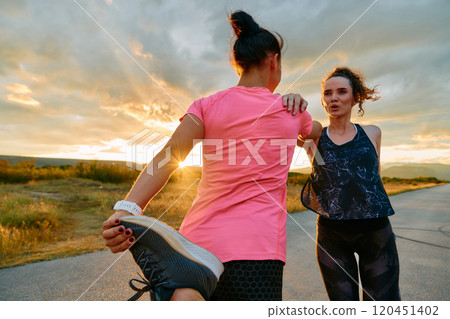 Two Women Athletes Stretching at Sunset in Beautiful Natural Surroundings Two Women Athletes Stretching at Sunset in Beautiful Natural Surroundings 120451402