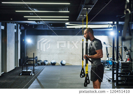 A muscular man in the gym, preparing for his workout, exudes determination and focus as he gets ready to push his limits and achieve his fitness goals. A muscular man in the gym, preparing for his workout, exudes determination and focus as he gets ready to push his limits and achieve his fitness goals. 120451410