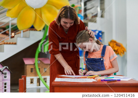 Creative kids during an art class in a daycare center or elementary school classroom drawing with female teacher. 120451416