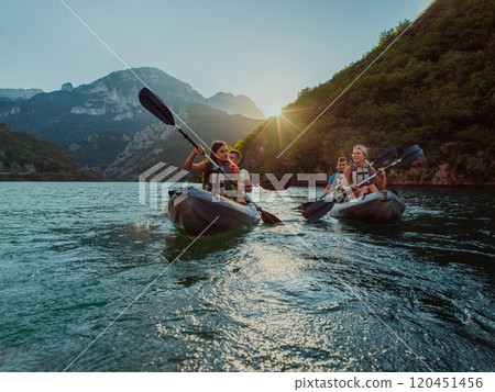 A group of friends enjoying fun and kayaking exploring the calm river, surrounding forest and large natural river canyons during an idyllic sunset. A group of friends enjoying fun and kayaking exploring the calm river, surrounding forest and large natural river canyons during an idyllic sunset. 120451456