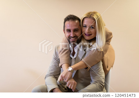 A business couple posing for a photograph together against a beige backdrop, capturing their professional partnership and creating a timeless image of unity and success. A business couple posing for a photograph together against a beige backdrop, capturing their professional partnership and creating a timeless image of unity and success. 120451473