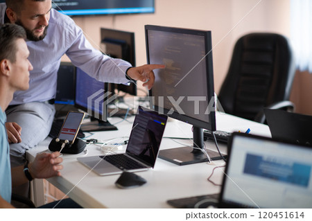 Programmers engrossed in deep collaboration, diligently working together to solve complex problems  120451614