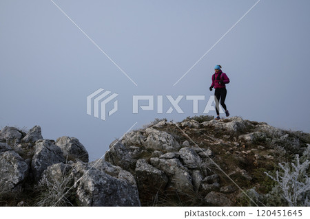 trail running woman athlete training for ultra-marathon race in a mountain 120451645