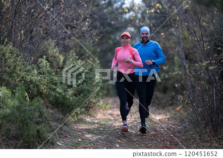 trail running with a sporty couple in the magic forest in early morning 120451652