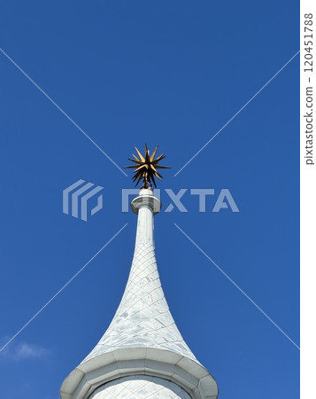 Ornate Tower Spire with Golden Star against Clear Blue Sky 120451788