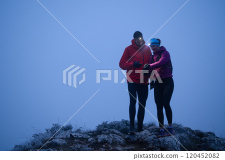Runners tired of breathing after training look at their tech sports smart watch in night on maintain  120452082