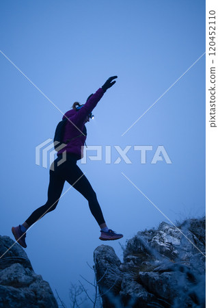 silhouette of a fitness woman trail runner jumping over a cliff and running to a rocky mountain top silhouette of a fitness woman trail runner jumping over a cliff and running to a rocky mountain top 120452110