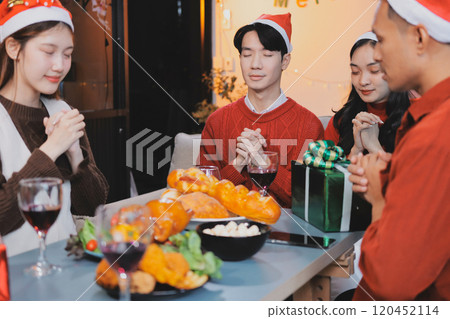 Group of young Asian man and women as friends having fun at a New Year's celebration, holding gift boxes standing by Christmas tree decoration, midnight countdown Party at home with holiday season. 120452114