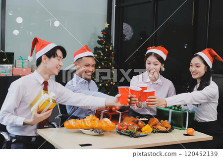 full length view of a group of business team wearing red Santa hat and exchange gift box together in the office for Christmas. 120452139