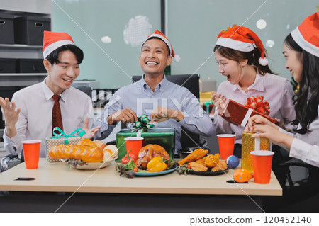 full length view of a group of business team wearing red Santa hat and exchange gift box together in the office for Christmas. full length view of a group of business team wearing red Santa hat and exchange gift box together in the office for Christmas. 120452140