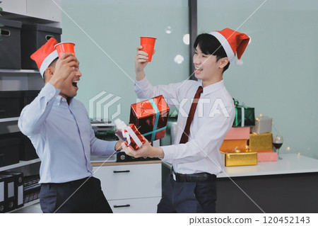 full length view of a group of business team wearing red Santa hat and exchange gift box together in the office for Christmas. full length view of a group of business team wearing red Santa hat and exchange gift box together in the office for Christmas. 120452143