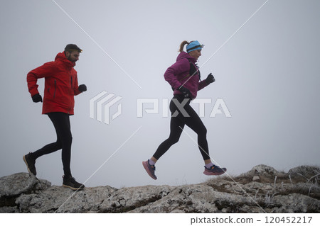 Athlete couple trail running on the mountain top in the early morning. Sky running concept Athlete couple trail running on the mountain top in the early morning. Sky running concept 120452217